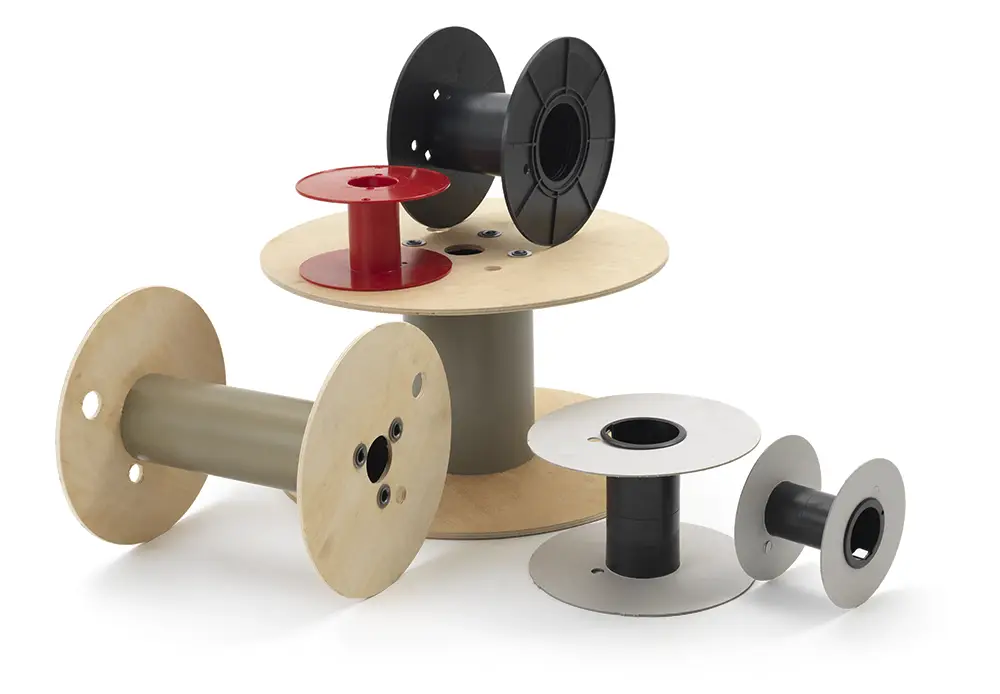 monplast-reels_group A groupage of empty reels for industrial electric cables, of different sizes, shapes, and colors, arranged on a neutral background.