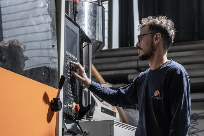 Un operatore visto dal basso che sta digitando un codice su un macchinario industriale.