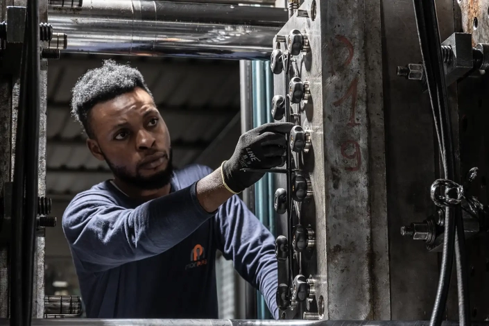 Un operatore tocca un volantino di serraggio in plastica in lavorazione, assieme ad altri, su un macchinario.