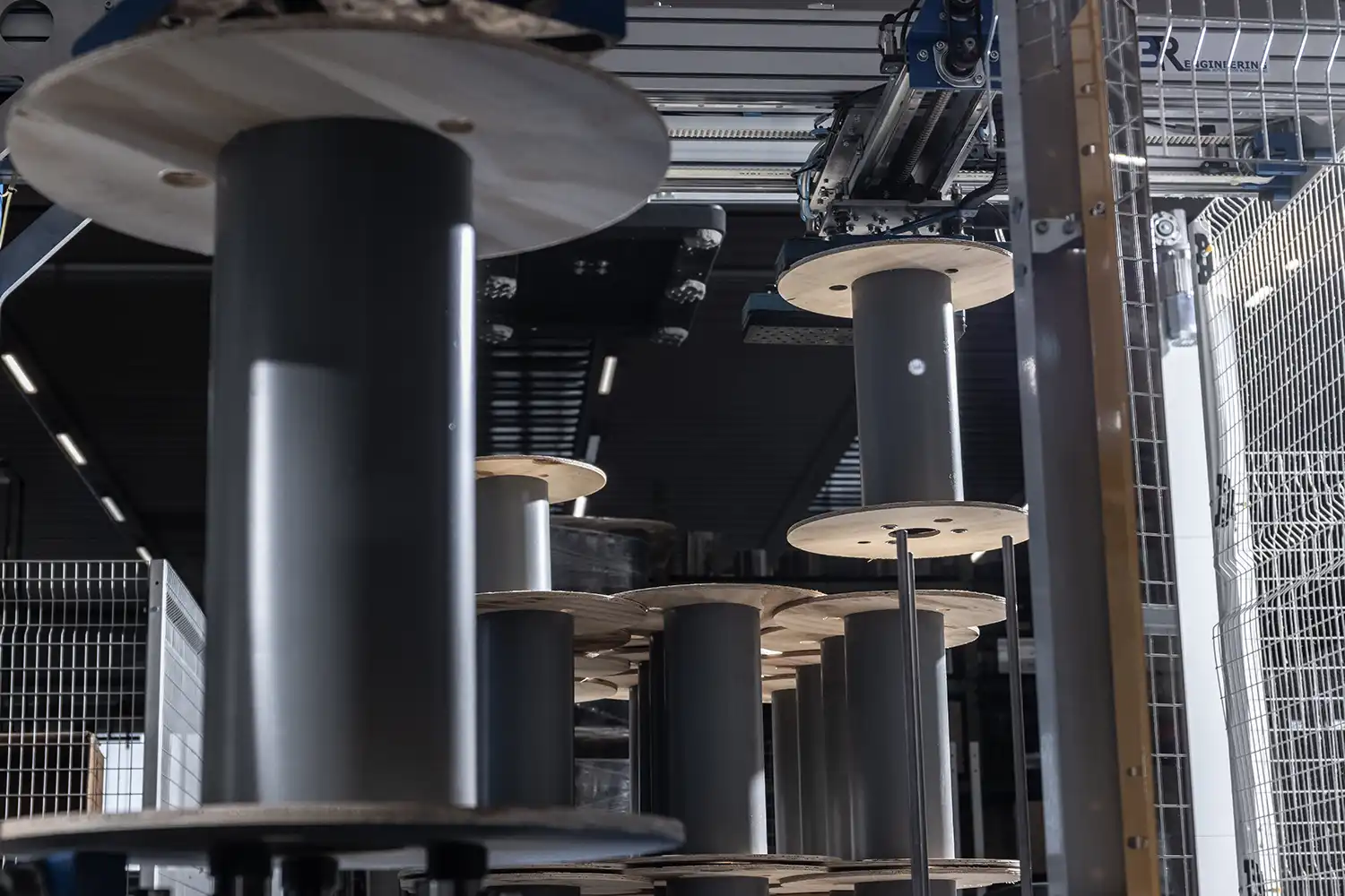 The interior of a factory with a detail of various empty plywood and plastic reels for industrial electrical cables stacked.