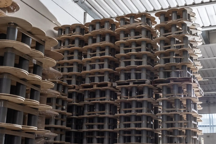 Monplast-8358-1500×1000 The interior of a factory with a detail of various stacks of empty plywood and plastic reels for industrial electric cables.