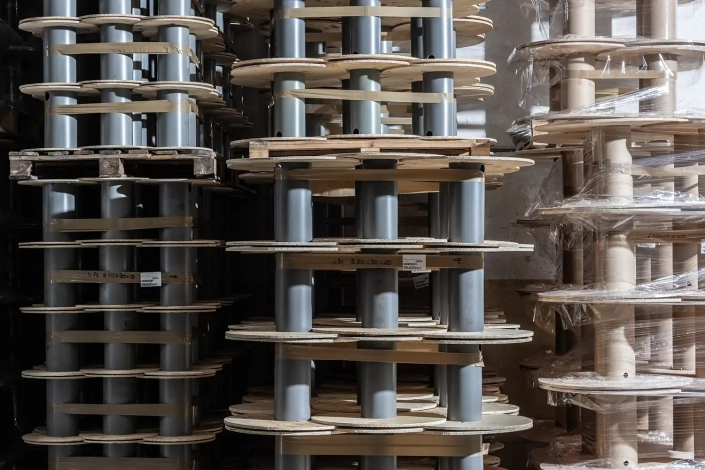 Monplast-8366-1500×1000 The interior of a factory with a detail of a stack of plywood and plastic and plywood and cardboard reels for industrial electric cables.