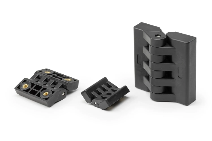 Three black hinges with bushings, of different sizes, arranged on a neutral background.