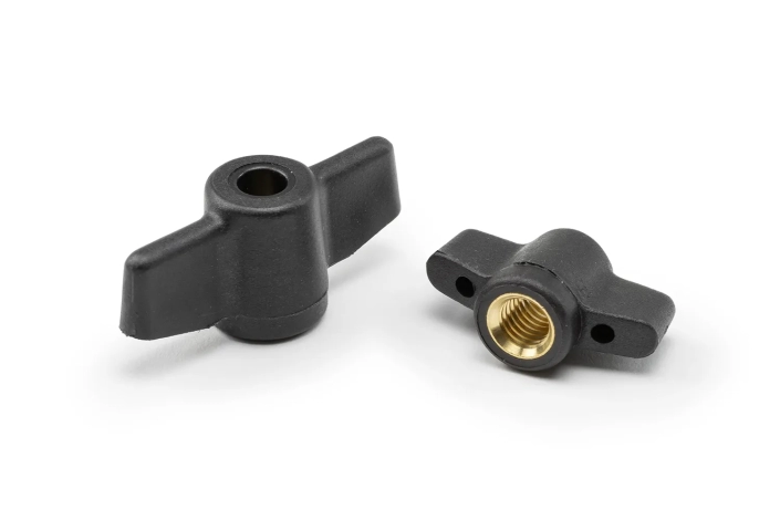 Two black wing nut fasteners with bushing and through hole arranged on a neutral background.