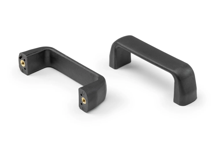 Two black plastic handles with bushing arranged on a neutral background.