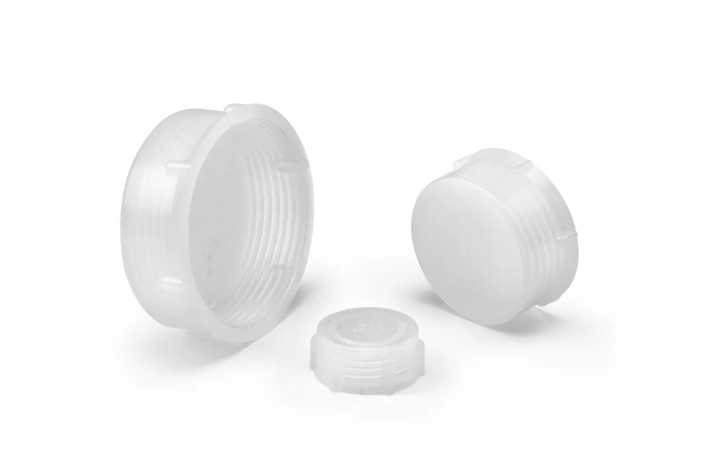 Three opaque transparent thread protection caps of different sizes arranged on a neutral background.