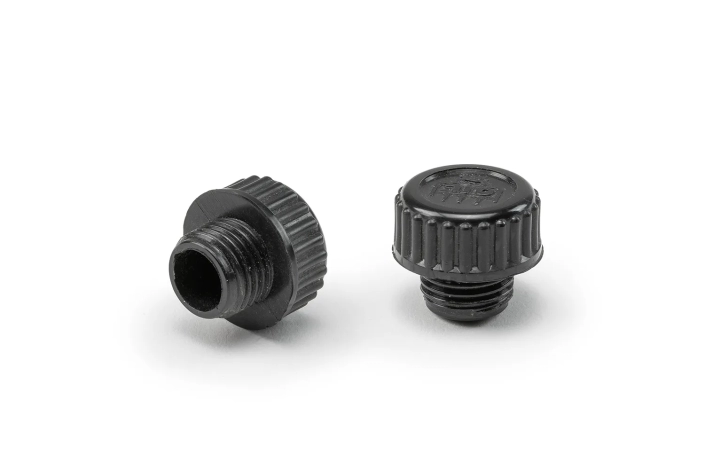 Two black oil drain plugs arranged on a neutral background.