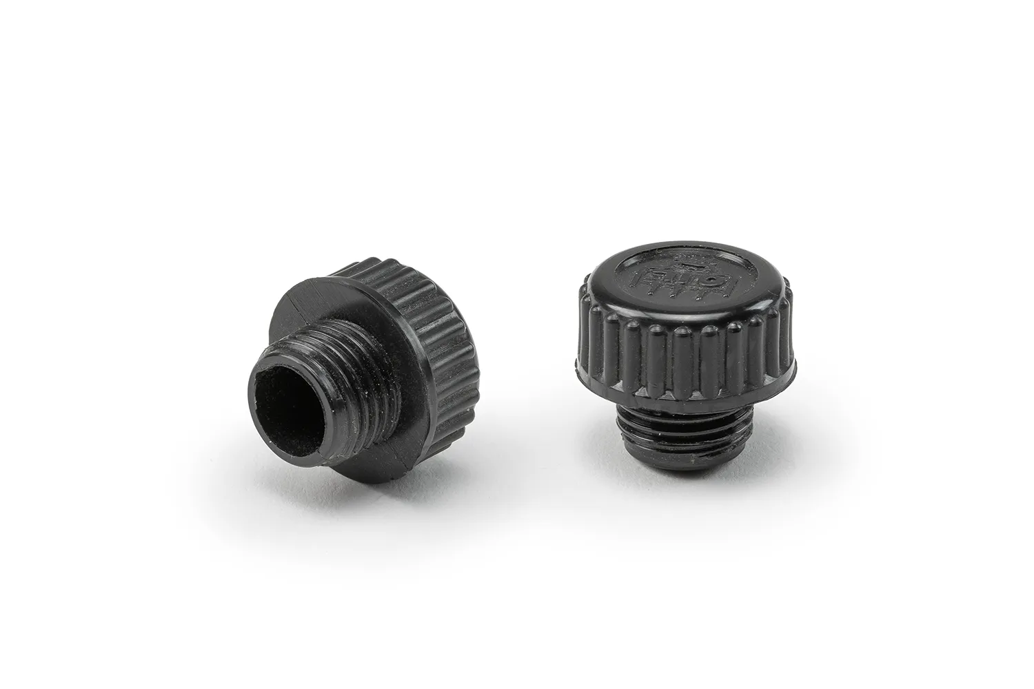 Two black oil drain plugs arranged on a neutral background.