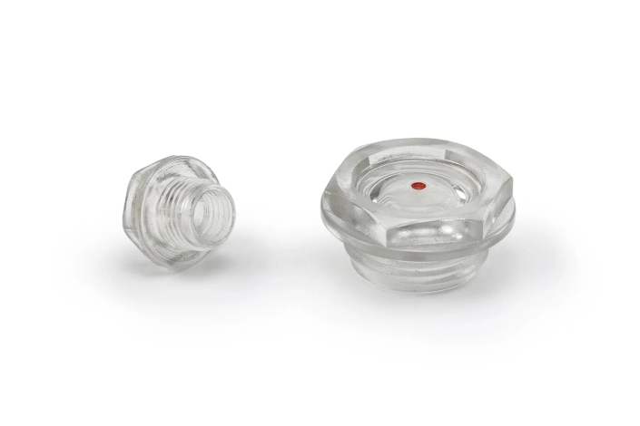 Two transparent oil level sight plugs of two different sizes, arranged on a neutral background.